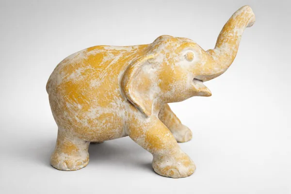 A pale gold elephant sculpture with its trunk raised